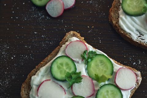 Assembling Cream Cheese Toast with Cucumber, Radish and Fresh Herb Garnish