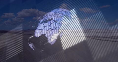 Futuristic holographic globe over desert dunes with grid overlay