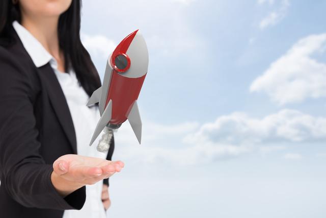 Businesswoman in professional attire holding and launching small rocket into sky symbolizes breakthrough, innovation, and ambition. Ideal for editorial pieces on business success, startup ventures, entrepreneurship, and strategic goals. Useful in marketing materials for tech companies, growth strategies, or inspirational content.