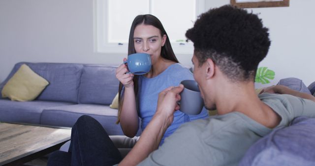 The couple is enjoying coffee in a comfortable yet casual living room. They are sitting on a couch, engaging in a relaxed conversation. This image can promote themes like home life, relationships, and everyday moments. Ideal for blogs or websites focusing on lifestyle, interior design, or mental wellbeing.
