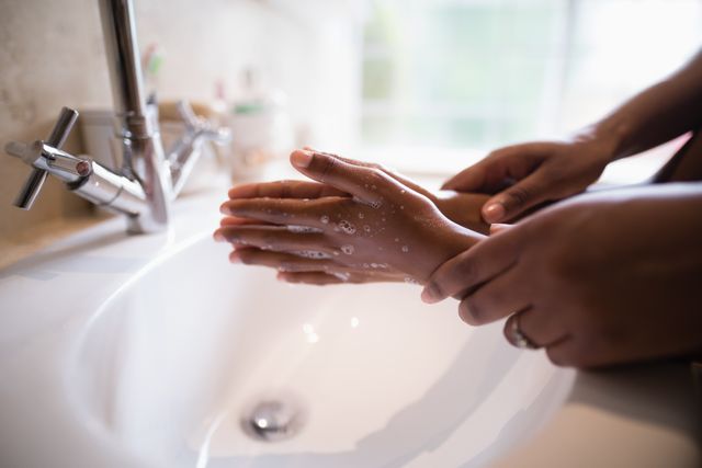 This image shows a mother assisting her daughter in washing hands at a bathroom sink. It highlights the importance of hygiene and parental guidance. Ideal for use in health and hygiene campaigns, parenting blogs, educational materials, and family-oriented advertisements.