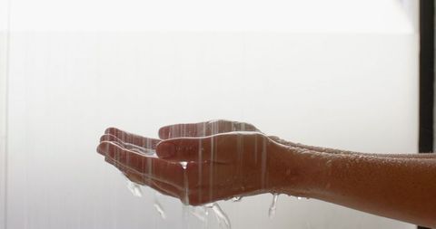 Hands Cupped Under Falling Water in Shower