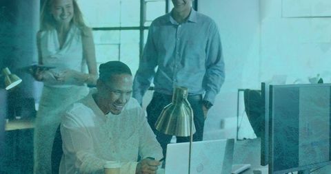 Smiling coworker checking smartphone while team collaborating around laptop in modern office