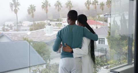 Couple Embracing on Balcony Overlooking Cityscape and Palm Trees