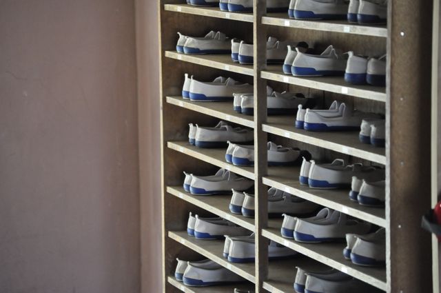 Storage shelves filled with white gym shoes, neatly arranged. An ideal scene for themes related to organization, fitness centers, sports, and school facilities. Perfect for illustrating concepts of neatness, preparation for physical activity, or the importance of keeping sports equipment organized.