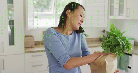 Multitasking woman talking on phone unpacking groceries in bright kitchen with fresh herbs
