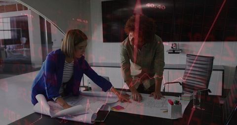 Team collaborating on blueprints with financial data overlay analyzing project impact
