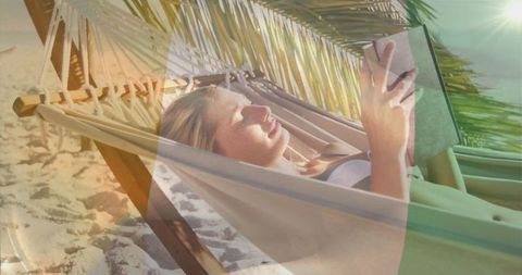 Woman relaxing in hammock with book on tropical beach