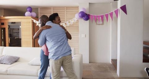 African American Couple Hugging in Cozy Living Room with Purple Party Decorations