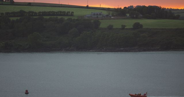 Sunset Over Serene Lakeside with Distant Boating Activity - Download Free Stock Images Pikwizard.com