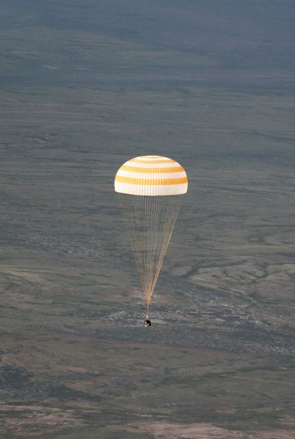 This image shows the Soyuz TMA-9 spacecraft descending slowly with its parachute open, floating over the expansive landscape of Kazakhstan. Captured on April 21, 2007, this scene marks the return of Expedition 14 commander Michael E. Lopez-Alegria, Soyuz commander Mikhail Tyurin, and spaceflight participant Charles Simonyi. This powerful shot would be ideal for use in discussions about space exploration, the role of international collaborations in space missions, or the details and experiences of space travel.