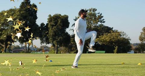 Male cricketer performing high-knee warmup on outfield with training cones and gold stars