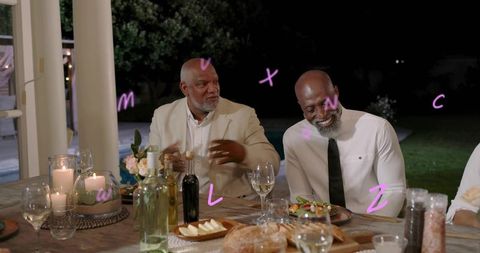 Elegant outdoor evening dinner with two men laughing at candlelit table with wine