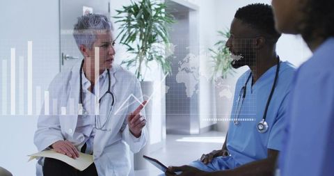 Senior physician pointing at holographic medical data while team reviewing tablet