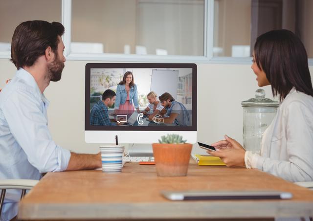Businesspeople engaging in a video chat during a meeting in a modern office setting. This could be used for illustrating concepts of remote communication, workplace technology, and corporate teamwork in presentations, articles, and promotional materials.
