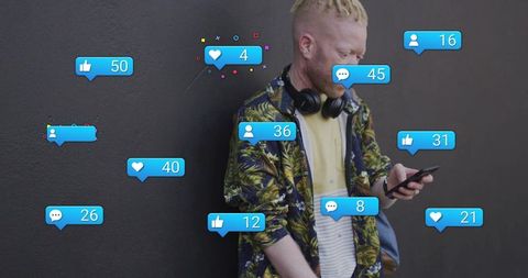 Young man checking smartphone with social media notifications floating around urban wall