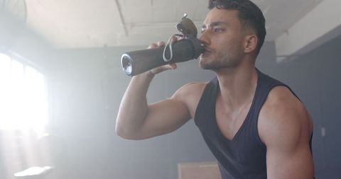 Fit Man Hydrating After Workout in Gym Setting