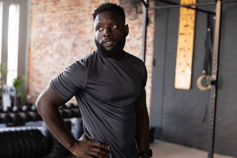 African american man resting between sets in industrial gym wearing wristwatch muscular