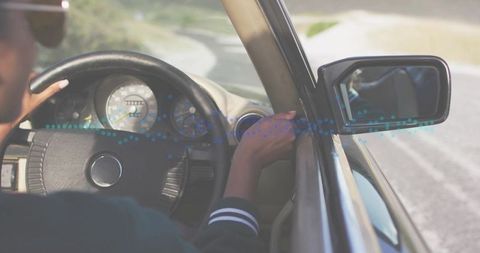 Female driver holding steering wheel driving car on sunlit road with dashboard gauge visible