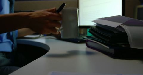 Busy Office Desk with Person Holding Coffee Mug Amidst Paperwork - Download Free Stock Images Pikwizard.com
