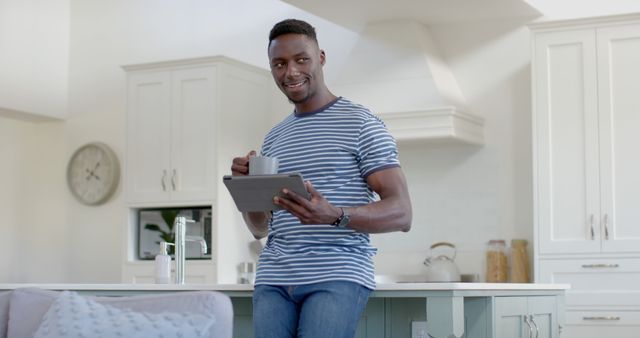 Smiling Black Man in Casual Clothes Holds Tablet in Modern Kitchen - Download Free Stock Images Pikwizard.com