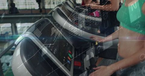 Woman adjusting treadmill console while pressing safety key and warming up in gym