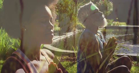 People of color meditating peacefully outdoors by a reflective pond