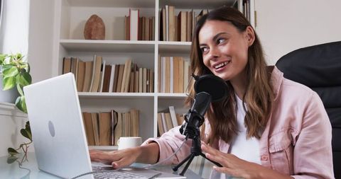 Smiling content creator recording podcast in modern home office
