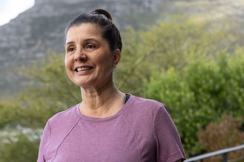 Middle-aged woman standing and smiling outdoors in mauve active top