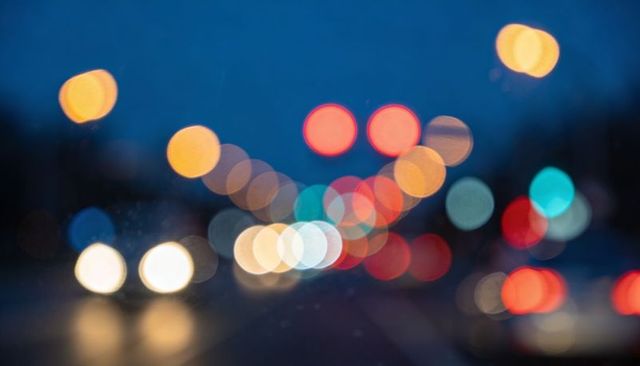 Glowing bokeh traffic lights blurring city roadway at dusk, colorful urban night scene