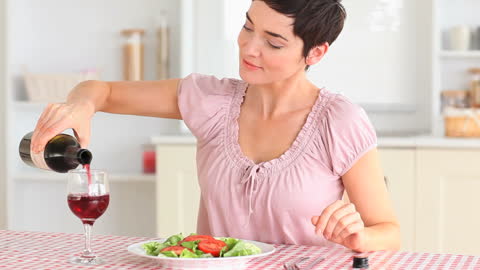 Woman Enjoying Red Wine and Fresh Salad at Home Table