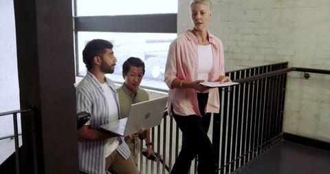 Diverse coworkers collaborating while climbing stairwell