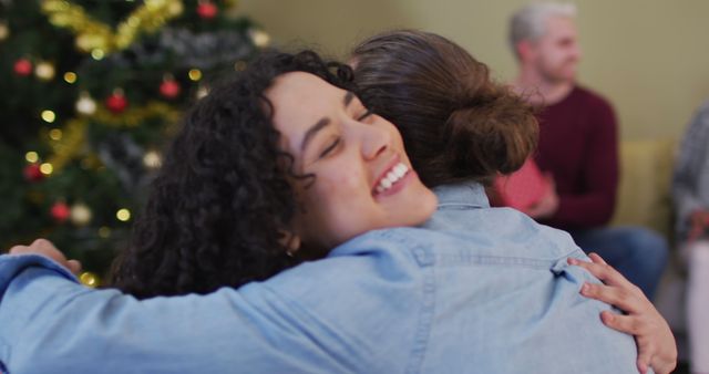 Young woman smiling while hugging a friend during a Christmas celebration. Perfect for holiday-themed promotions, advertisements focusing on friendship and togetherness during the festive season, and social media posts celebrating Christmas joy.