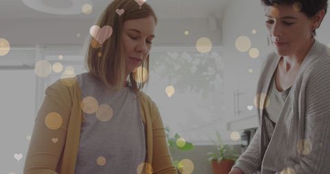 Caucasian female couple making coffee with heart graphics