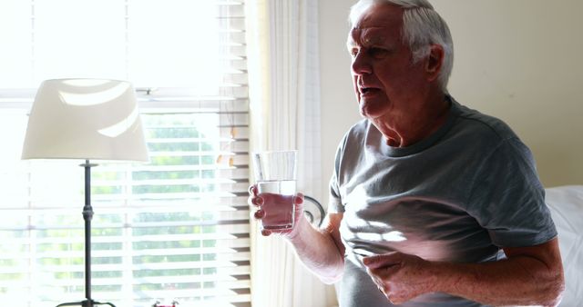 Senior Man Holding Glass of Water Indoors Near Window - Download Free Stock Images Pikwizard.com