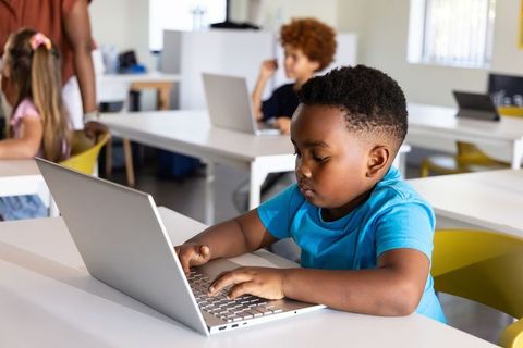 African American Boy Using Laptop in Bright Classroom Learning Tech Skills and Coding