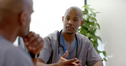 African american clinician conducting patient consultation in clinic wearing grey scrubs
