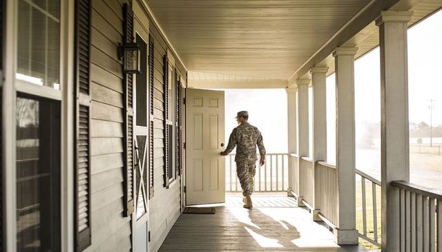 Soldier returning home opening front door on sunlit rural porch at sunrise