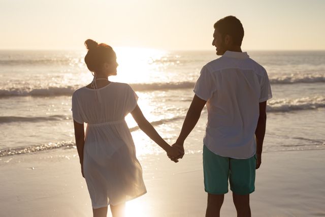 Couple standing together hand in hand on the beach - Download Free Stock Photos Pikwizard.com