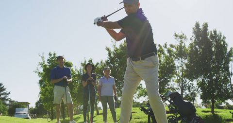 Senior Man Practicing Golf with Friends on Sunny Day