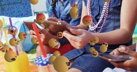 Children Using Smartphones Outdoors Surrounded by Virtual Emojis
