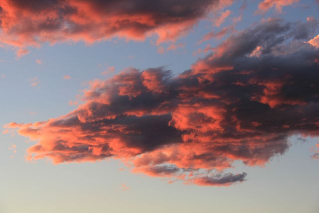 Depicting vibrant and dramatic clouds illuminated by setting sunlight, this image captures the natural beauty of an evening sky transitioning to dusk. This can be used for nature and landscape photography websites, evening-themed projects, and digital or print backgrounds illustrating serene and tranquil atmospheres.