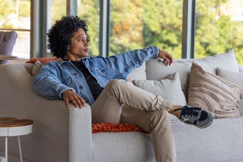 African american man relaxing on modern neutral sofa in bright minimalist living room