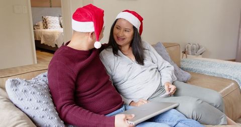 Expectant Couple in Santa Hats with Ultrasound Celebrating on Couch