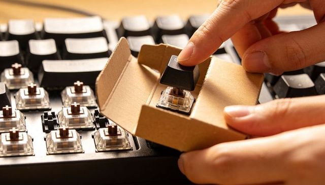 Placing black keycap onto mechanical switch closeup showing brown stem for modding