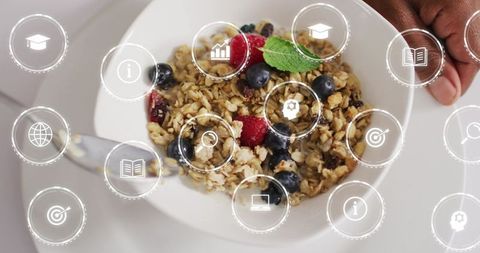 Hand holding bowl of granola with berries and overlay hud icons for healthy breakfast