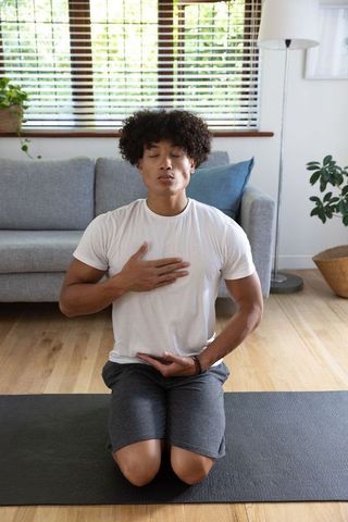 Mindful african american man practicing breathing techniques at home
