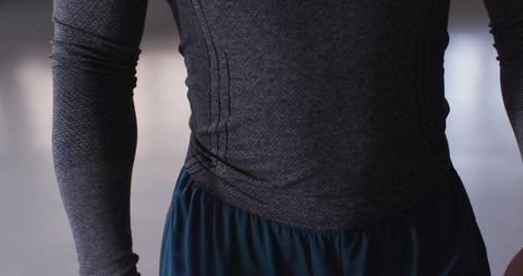 Contemporary dancer wearing fitted gray top and flowing blue pants rehearsing on reflective floor