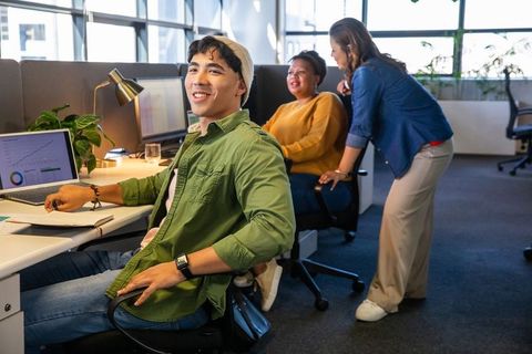 Young multicultural team collaborating in bright open-plan office reviewing laptop data