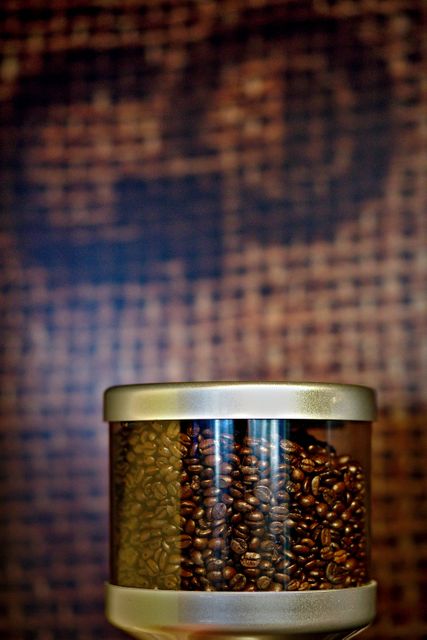 Close-up of coffee beans in grinder interior with blurred background can be used in advertising for coffee shops, brewing equipment brands, and coffee-related products. Ideal for illustrating concepts of freshness, quality, and brewing processes.